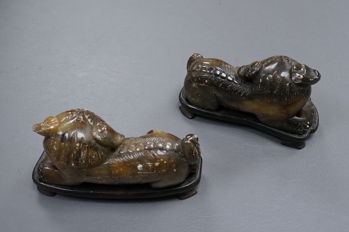A pair of Chinese soapstone figures of lion dogs, on wood stands, 11cm wide
